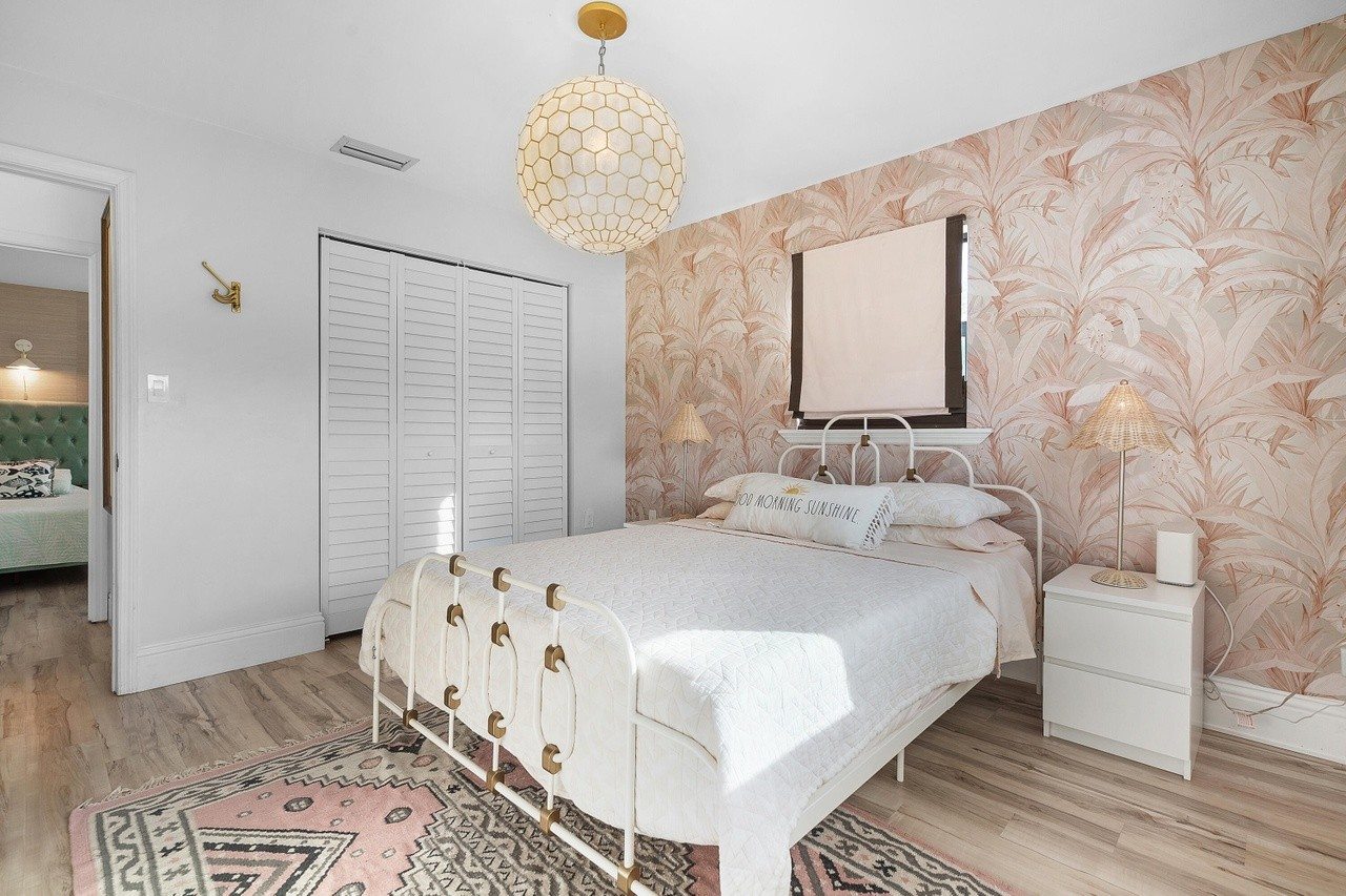 Guest bedroom with botanical wallpaper and a brass bed