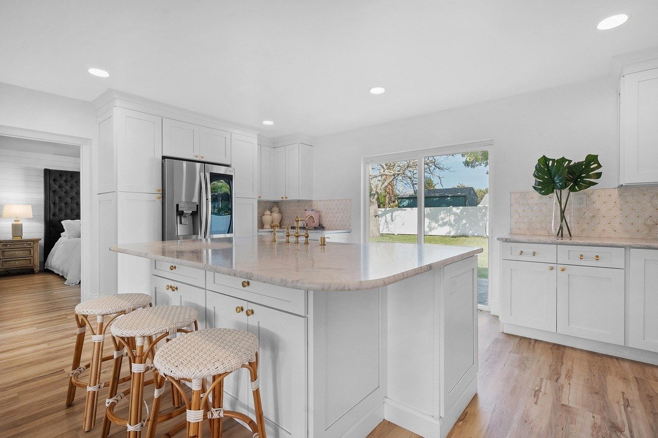 White kitchen with a broad island and three stools